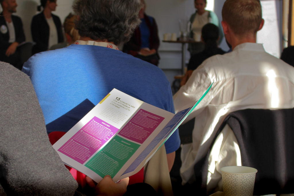 Person bläddrar i Tag Plats! rapporten under seminarium